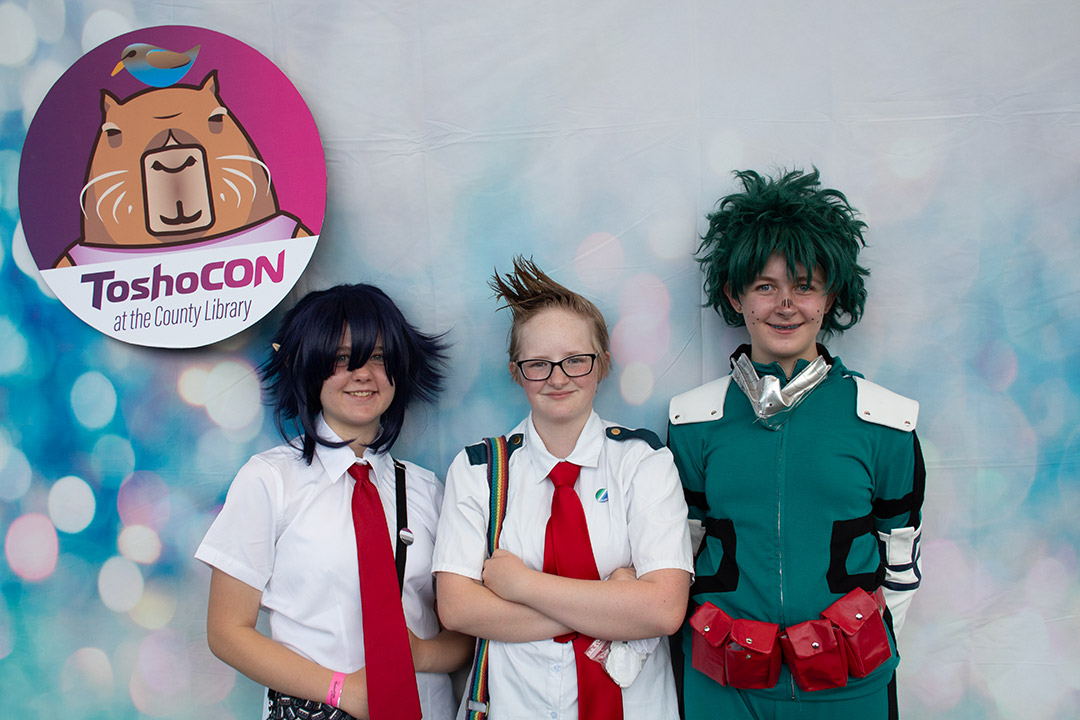 Cosplayers pose in front of a backdrop